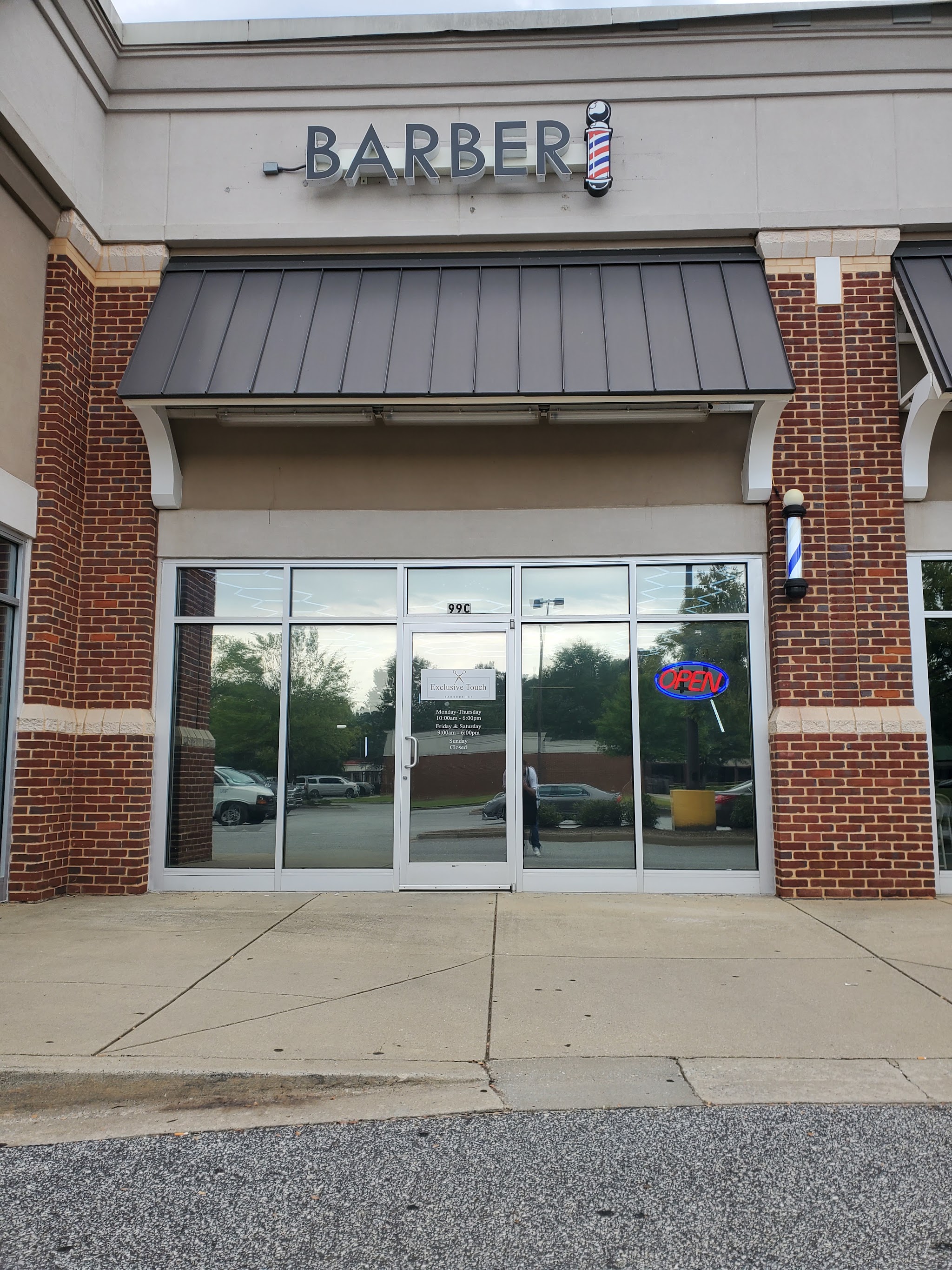 Brick storefront with glass doors and a barber pole sign on Garner Rd